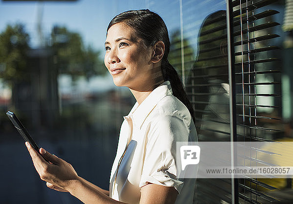 Lächelnde Geschäftsfrau benutzt digitales Tablet im Freien