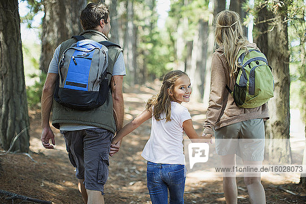 Lächelndes Mädchen wandert mit Eltern im Wald