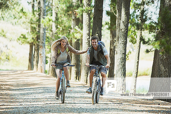 Smiling couple mountain biking in woods