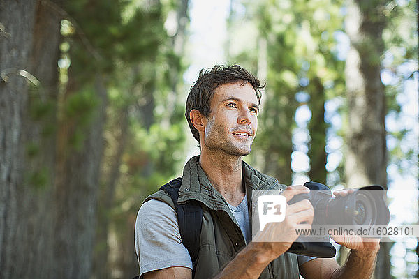 Mann mit Digitalkamera im Wald