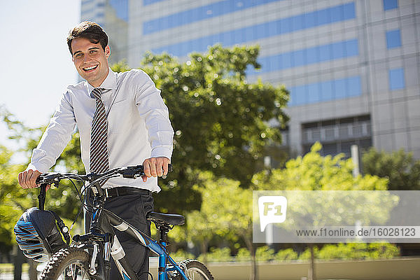 Smiling businessman with bicycle outdoors