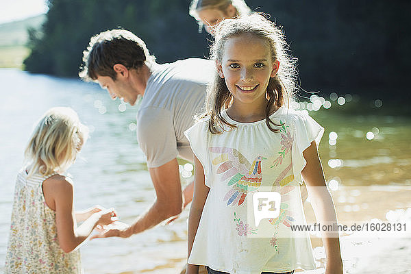 Lächelndes Mädchen mit Familie am Seeufer