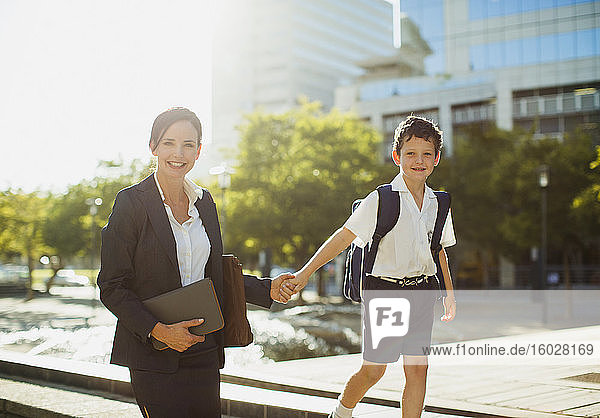 Lächelnde Geschäftsfrau geht mit Sohn im Freien spazieren