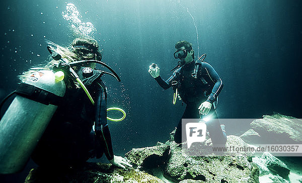 Unterwasseraufnahme von zwei Tauchern in Taucheranzügen  Taucherbrille und Sauerstoffflaschen.