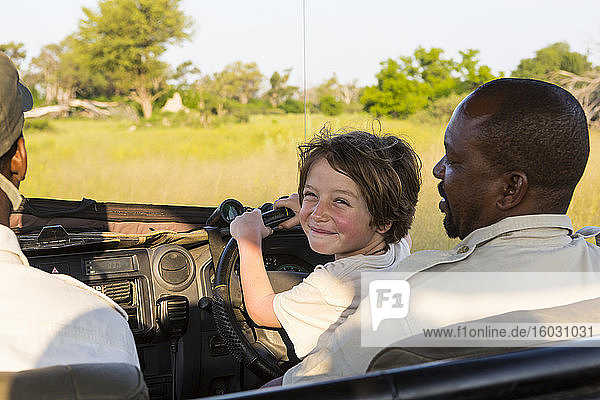 smiling Six year old boy steering safari vehicle  Botswana