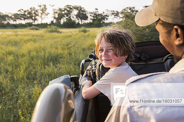 lächelnder sechsjähriger Junge lenkt Safari-Fahrzeug  Botswana