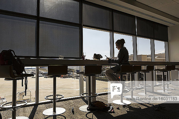 Eine reife Frau  weibliche Führungskraft sitzt mit einem Laptop in der Abflughalle eines Flughafens