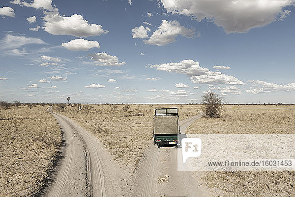 Ein Safari-Fahrzeug an einer Weggabelung in den vor uns liegenden Gleisen auf offenem Gelände.