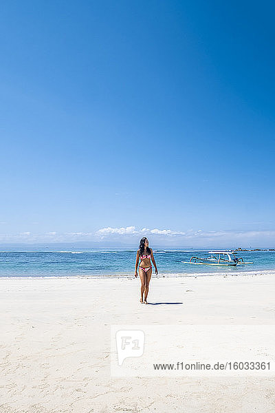 Eine schöne asiatische Frau reist allein im Bikini an einem unberührten tropischen Strand  Bali  Indonesien  Südostasien  Asien
