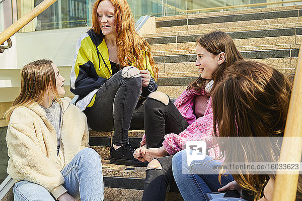 Group of teenage girls sitting on staircase in a shopping mall  chatting.