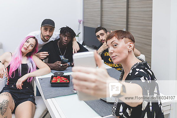 Gruppe junger Freunde  die am Tisch sitzen und ein Selfie machen.