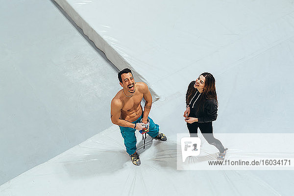 Hochwinkelaufnahme einer Frau und eines Mannes  die vor einer Indoor-Felskletterwand stehen.