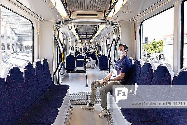Man wearing face mask sitting in an empty train in Florence  Italy during the Corona virus crisis.