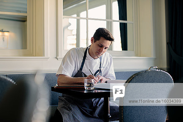 Junger männlicher Chefkoch schreibt im Restaurant die Speisekarte