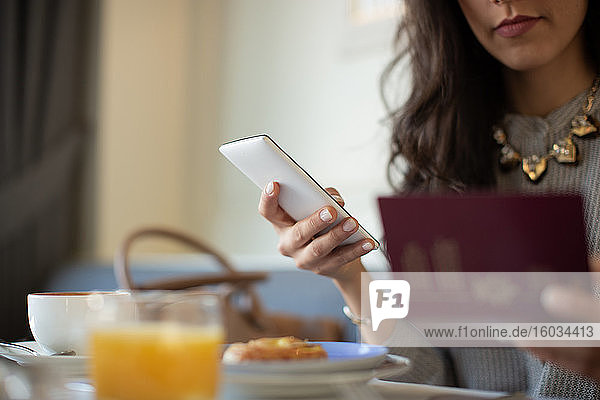 Geschnittene Aufnahme einer jungen Frau mit digitalem Tablett beim elektronischen Einchecken während des Frühstücks in einem Boutique-Hotel in Italien