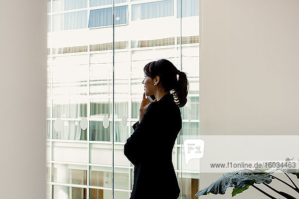 Businesswoman using mobile phone by window