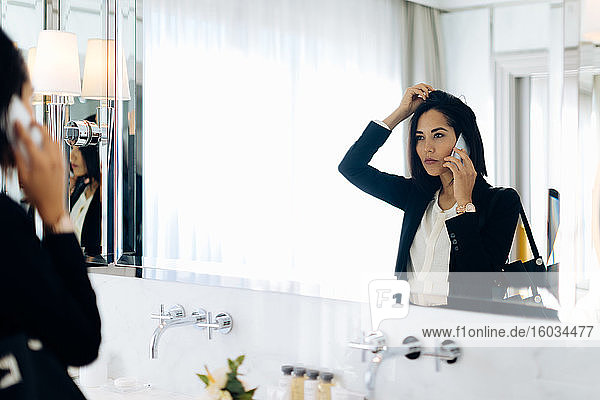 Geschäftsfrau benutzt Smartphone im Badezimmer der Suite