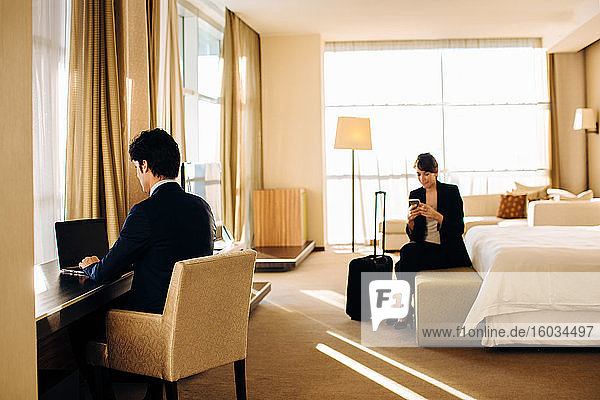 Businessman and businesswoman working in hotel bedroom