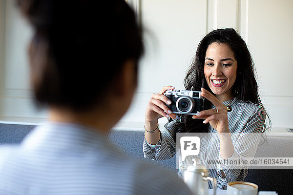 Young woman photographing friend whilst having breakfast in boutique hotel in Italy