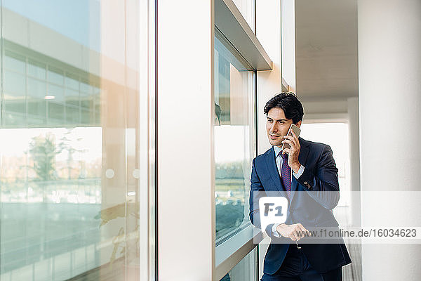 Geschäftsmann mit Mobiltelefon am Fenster