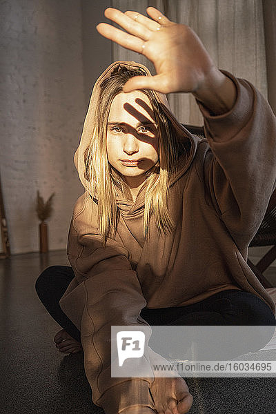 Porträt einer selbstbewussten jungen Frau mit Kapuzen-Sweatshirt das die Sonne mit der Hand abhält
