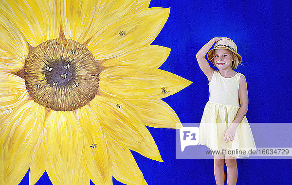 Porträt eines fröhlichen Mädchens in gelbem Kleid vor gemaltem Sonnenblumenhintergrund