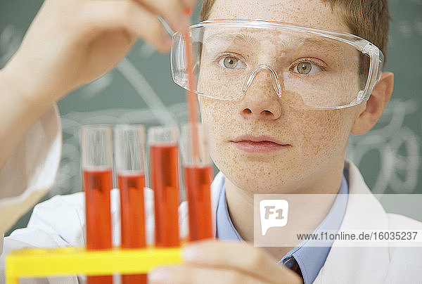 Neugieriger Junge aus der Junior High School untersucht Flüssigkeit in wissenschaftlichen Reagenzgläsern