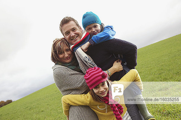 Porträt einer glücklichen Familie  die sich im Grasfeld umarmt