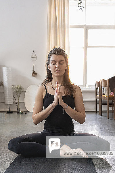 Gelassene junge Frau meditiert auf Yogamatte
