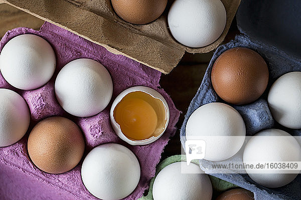 Weiße und braune Eier in Eierkartons  eines aufgeschlagen