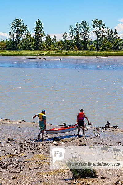 Zwei Männer lassen ihre Kajaks in einem ausgebaggerten Kanal in Steveston British Columbia zu Wasser.
