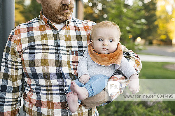 Outdoor portrait of baby boy carried by father