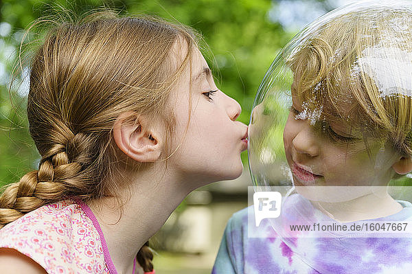 Girl kissing boy wearing bubble to socially distance