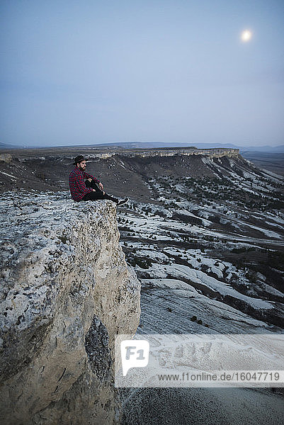 Ukraine  Crimea  Hiker sitting on edge of steep cliff near White Mountain