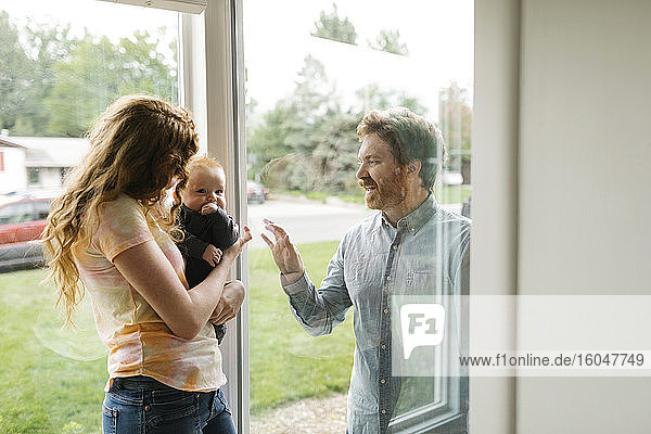Vater besucht Partner und Sohn (6-11 Monate) durch Fenster
