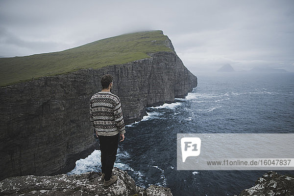 Dänemark  Färöer-Inseln  Sorvagur  Mann schaut auf Meeresküste mit Klippen