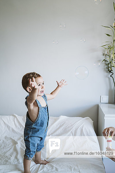 Baby girl playing with bubbles at home