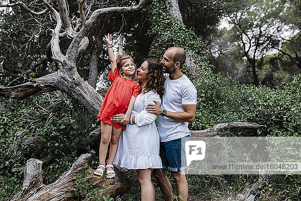 Eltern sehen ihre Tochter auf einem umgestürzten Baum im Wald stehen