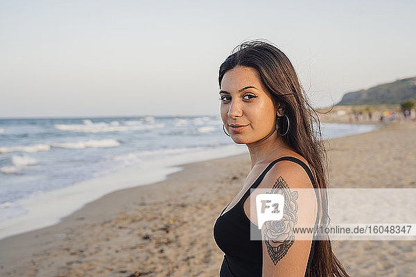 Beautiful teenage girl standing at beach against clear sky