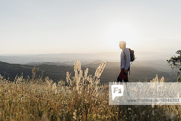 Senior man standing on mountain while hiking during sunset