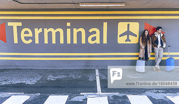 Geschäftspaar mit Gepäck im Flughafenterminal stehend