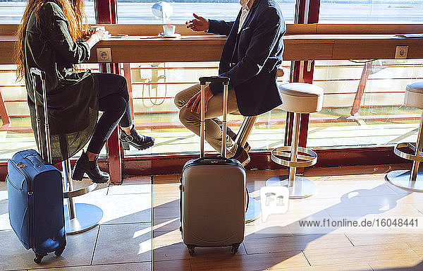 Geschäftspaar sitzt mit Gepäck im Flughafencafé