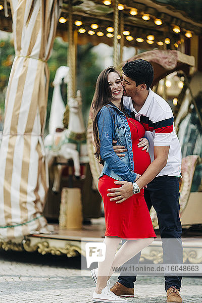 Glücklicher Mann küsst schwangere Frau vor einem Vergnügungspark  Cascais  Portugal