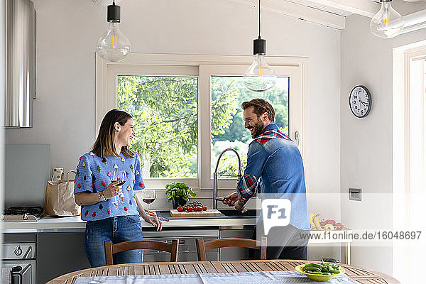 Lächelndes mittleres erwachsenes Paar im Gespräch in der Küche zu Hause