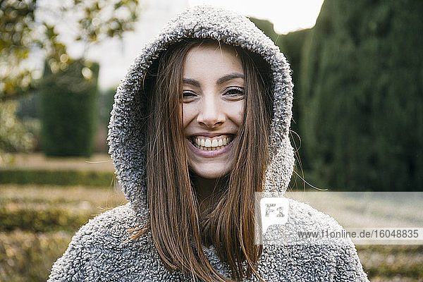 Close-up of cheerful beautiful woman wearing hood in park during winter