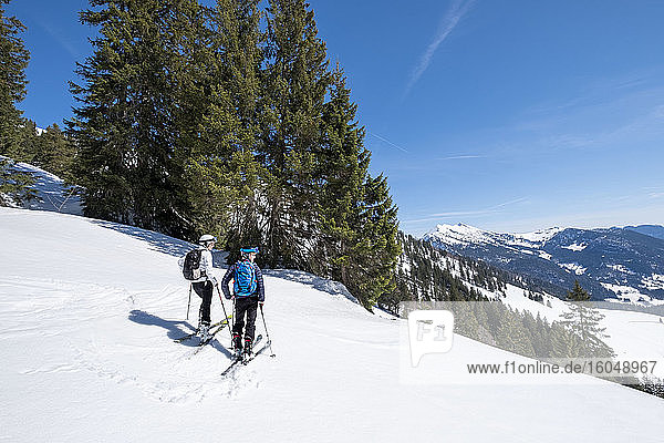 Mutter und Sohn beim Skifahren auf einem verschneiten Berg gegen den Himmel  Berchtesgaden  Bayern  Deutschland