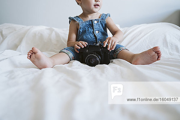 Baby girl holding camera at home