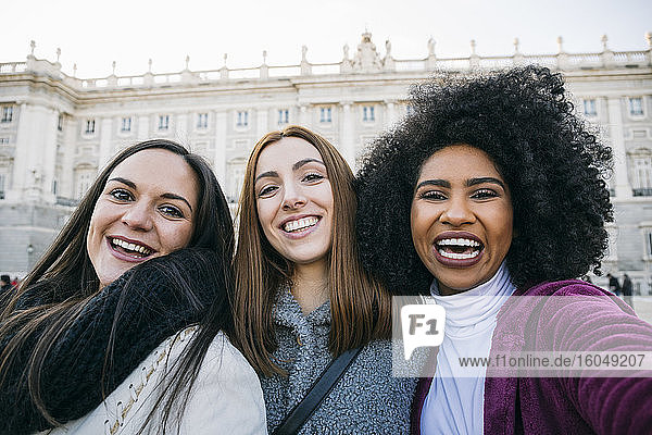 Cheerful female friends standing against Madrid Royal Palace  Spain