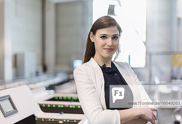 Confident businesswoman with arms crossed standing in factory