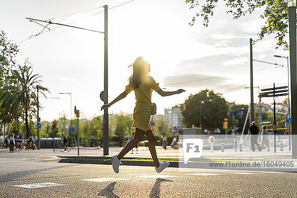 Junge Frau läuft an einem sonnigen Tag auf einer Straße in der Stadt